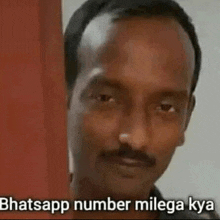 a man with a mustache is standing in front of a door with the words `` whatsapp number milega kya '' written on it .