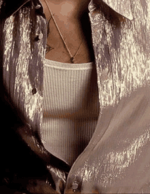 a close up of a person wearing a gold shirt and a white tank top