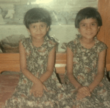 two little girls are sitting next to each other and smiling