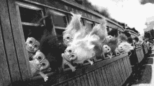 a black and white photo of a train with trolls sticking their heads out of the windows .