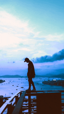 a man is standing on a ledge overlooking a body of water