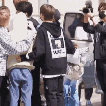 a group of people are standing in front of a van and a man is taking a picture of them .