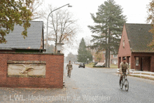 two soldiers are walking down a street in front of a building that says lwl-medienzentrum for westfalen