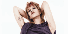 a woman with a pentagram tattoo on her arm looks at the camera