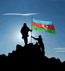 two soldiers holding a flag on top of a rocky hill