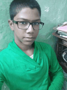 a young boy wearing glasses and a green shirt with the letter c on it