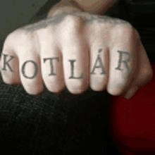 a close up of a person 's fist with the word kotlar tattooed on it