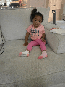 a little girl sits on a couch wearing a shirt that says rockin ' roots