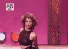 a woman is dancing on a stage with a pink background and a tv pg logo in the background .