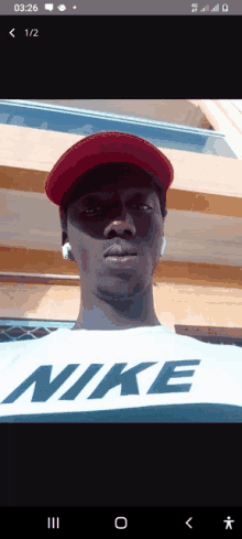 a man wearing a nike shirt and a red hat looks at the camera