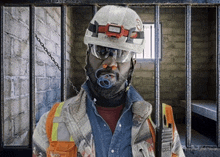 a man with a pacifier in his mouth wearing a hard hat and goggles