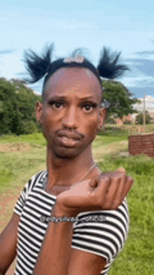 a man with pigtails on his head is wearing a striped shirt .