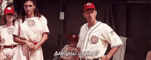 a group of baseball players are standing in a dugout and one of them is asking another player if they are crying .