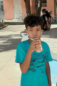 a young boy wearing a blue shirt that says holidays drinks from a cup