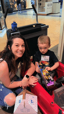 a woman sits next to a young boy in a toy car with a name tag that says ' ryan ' on it