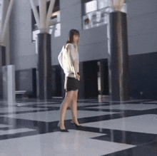 a woman walking on a checkered floor with columns in the background