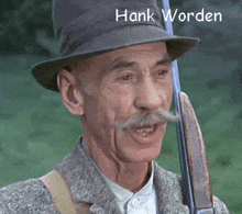 a man with a hat and mustache is holding a gun and the name hank worden is on the bottom