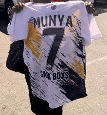 a person is holding a jersey that says munya on it