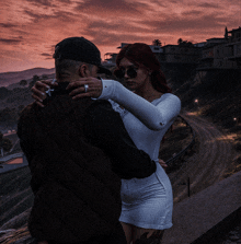 a man and woman are hugging each other in front of a sunset