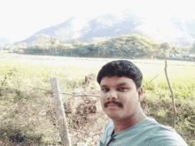 a man with a mustache stands in front of a field