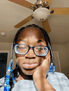 a woman wearing glasses and blue beads looks at the camera