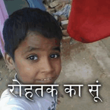 a young boy is taking a selfie with a sign in a foreign language behind him .