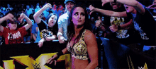 a woman in a wrestling outfit is standing in front of a crowd and giving a thumbs up .