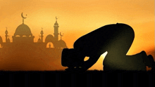 a silhouette of a man praying in front of a mosque at sunset