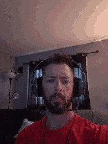 a man wearing headphones and a red shirt looks down at the camera