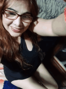 a woman wearing glasses and a black tank top takes a selfie