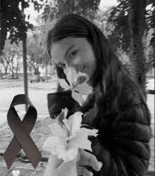 a black and white photo of a girl holding flowers with a black ribbon behind her