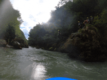 a group of people in yellow helmets are standing on a cliff overlooking a river