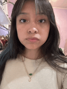 a woman wearing a white shirt and a green necklace