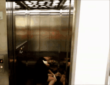 a woman sits in an elevator with a sign on the wall that says ' emergency exit '