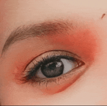 a close up of a person 's eye with red eye shadow