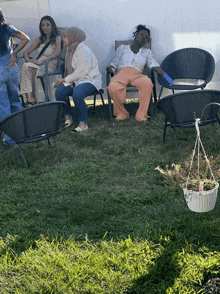 a group of women are sitting in chairs in a grassy area