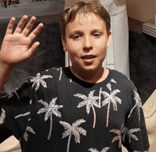 a boy wearing a shirt with palm trees on it