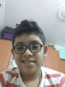 a young boy wearing glasses and earphones smiles for the camera