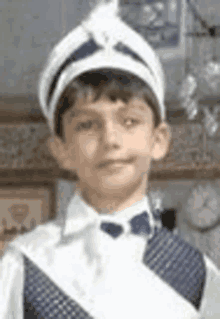 a young boy is wearing a white hat and a blue vest .