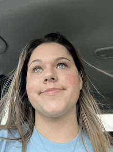 a woman with blue eyes and red cheeks is smiling for the camera