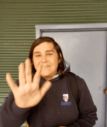 a woman wearing a sweatshirt that says ' liberty ' on it waves her hand