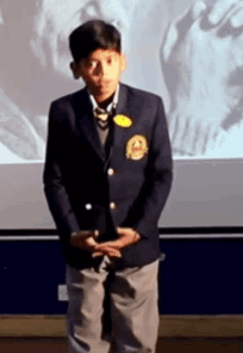 a young boy in a school uniform has a yellow badge on his jacket