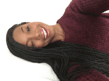 a woman with braids is smiling while wearing a burgundy sweater