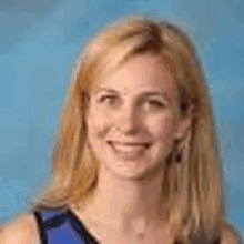 a woman with long blonde hair is smiling for the camera while wearing a blue shirt .