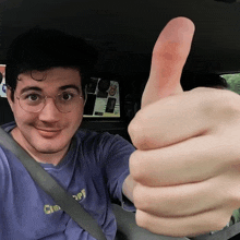 a man giving a thumbs up in a car wearing a shirt that says cheer