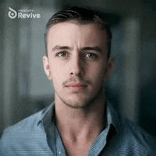 a man in a blue shirt is looking at the camera with the words made with revive behind him .