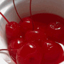 a bowl filled with red cherries in a red liquid