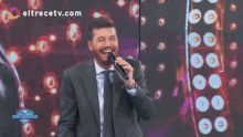 a man singing into a microphone with eltrecetv.com on the bottom right