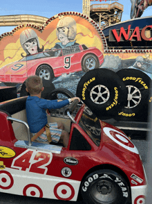 a little boy is driving a red race car with good year tires