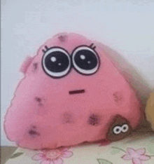 a pink stuffed animal with big eyes is sitting on top of a table .